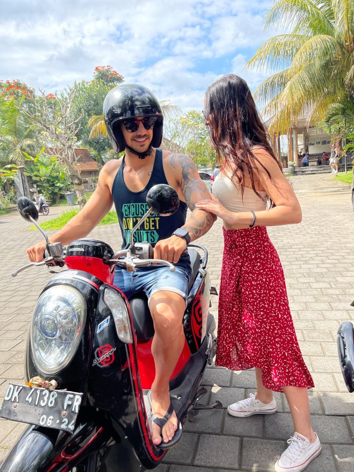 ruta por indonesia dos personas un chico subido en una moto con casco y una chica con falda larga roja que va a subir